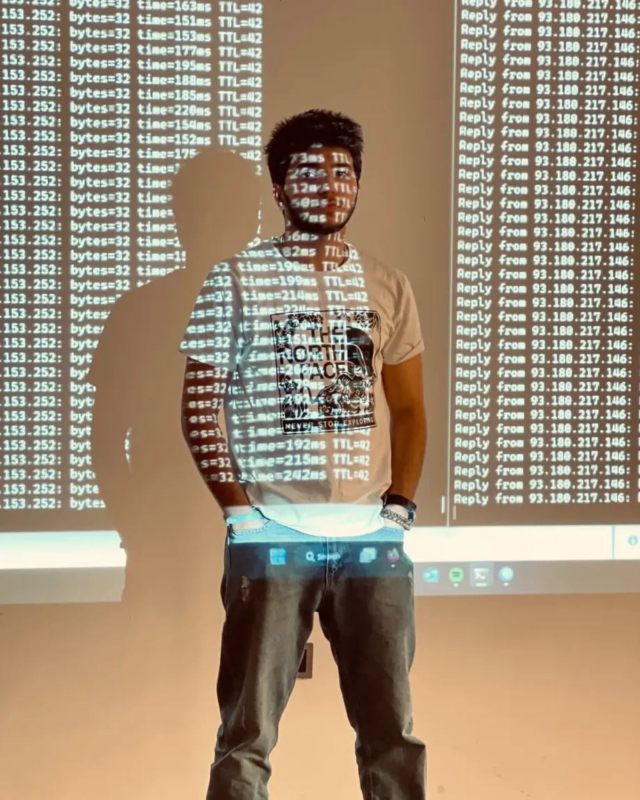 Ahmed Shakir standing in front of a projected terminal running ping